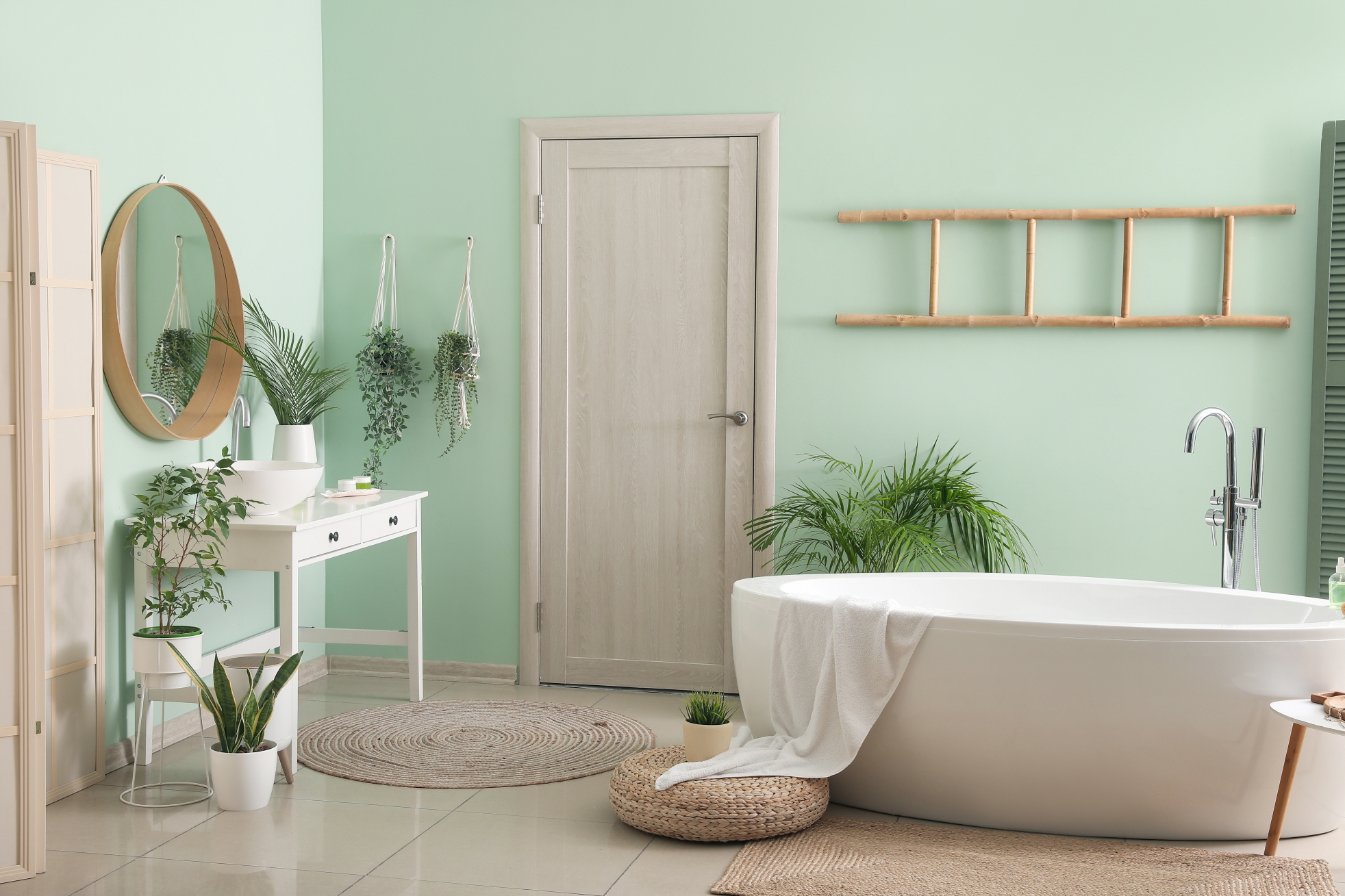 Enhance the ambiance of the space by placing potted tree plants around the freestanding bathtub.