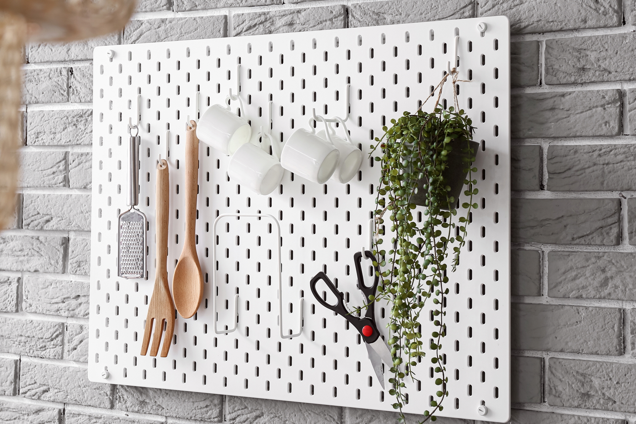 A vertical pegboard is an innovative way to hang essentials in the kitchen, effectively decluttering counter space.